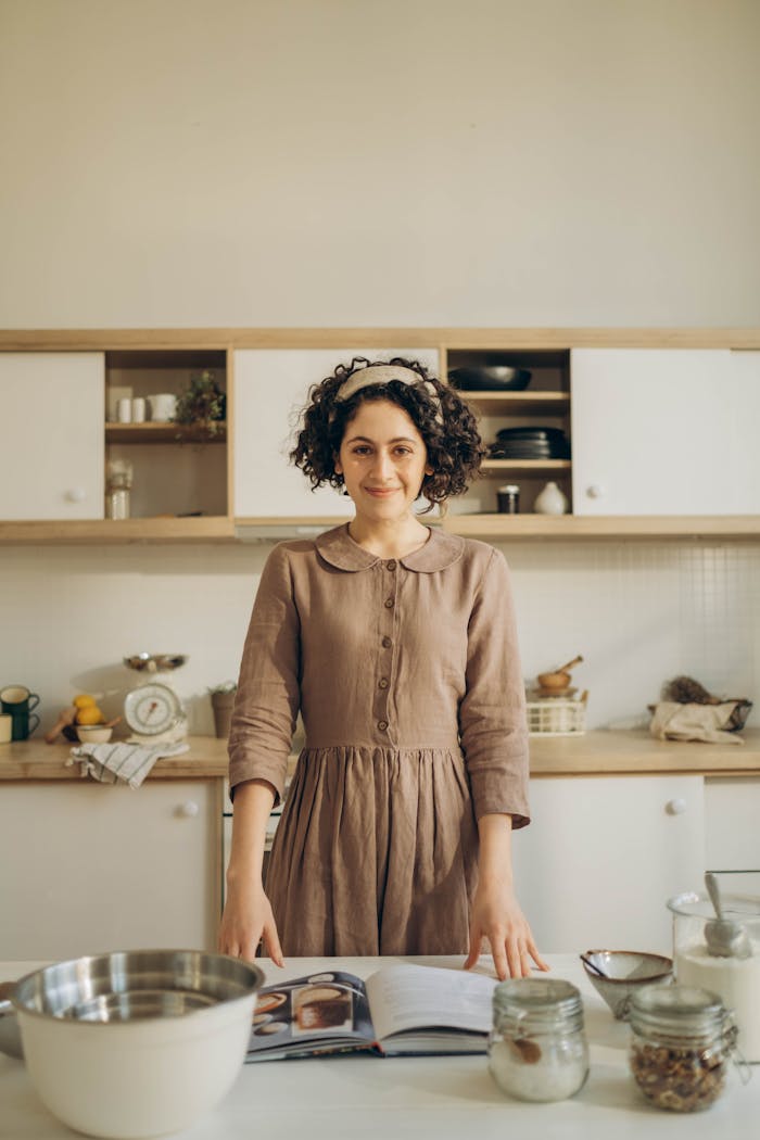 A joyful woman enjoying cooking at home in a cozy kitchen setting with various kitchenware.